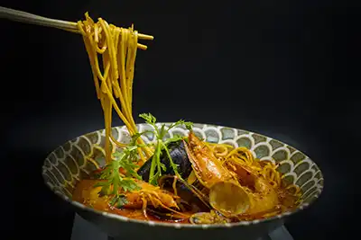 Una de las especialidades de la Chef Zoe. Caldo de vaca o vegetal con mas de 8 horas de preparación a fuego lento. Mejillones, almejas, pulpo, calamar, langostinos, pescado, huevo, algas, cebollino, zanahoria, col, pimiento, verduras del tiempo y tallarines. Este ramen concretamente lleva una elaboración especial de un picante casero de mas de 5 horas que lo convierte en la esencia del ramen. Se puede pedir poco o muy picante.. simplemente espectacular (Se puede suprimir la exencia de vaca)