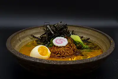 Delicioso ramen con caldo de más de 24 horas cocinado a fuego lento, servido con verduras, tallarines, naruto, láminas de pescado, huevo y algas, cerdo y pollo molido con un picante casero elaborado durante más de 4 horas y media. Polvo picante casero especial 'Kimchi' salteado con una salsa de la casa