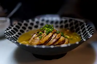 Delicioso ramen con caldo elaborado durante más de 24 horas a fuego lento, la carne chashu cocinada con una sabrosa salsa dulce es perfecta tanto para el ramen como para el cuenco de arroz blanco sobre el que se sirve este delicioso ramen con tallarines, verduras de temporada,algas, naruto lámina de pescado