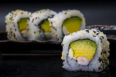 Makis rellenos de aguacate, langostino, mayonesa y cubiertos de sésamo
